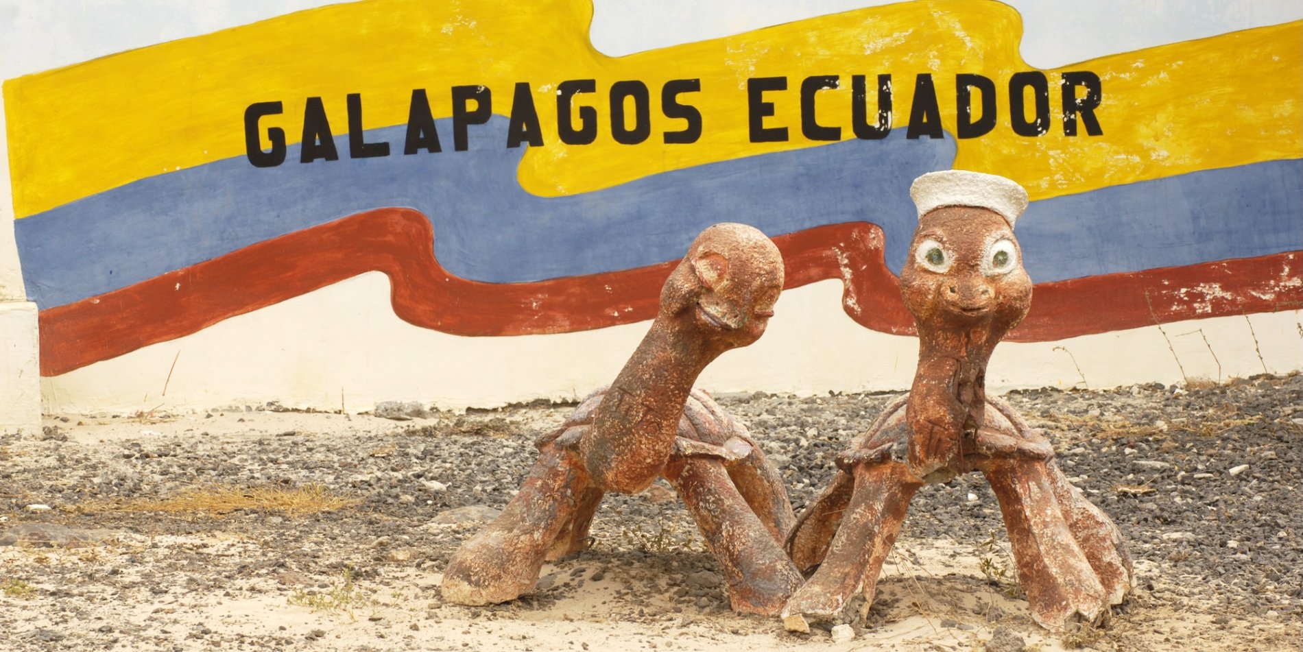 A Galapagos Islands sign with two stone turtles.