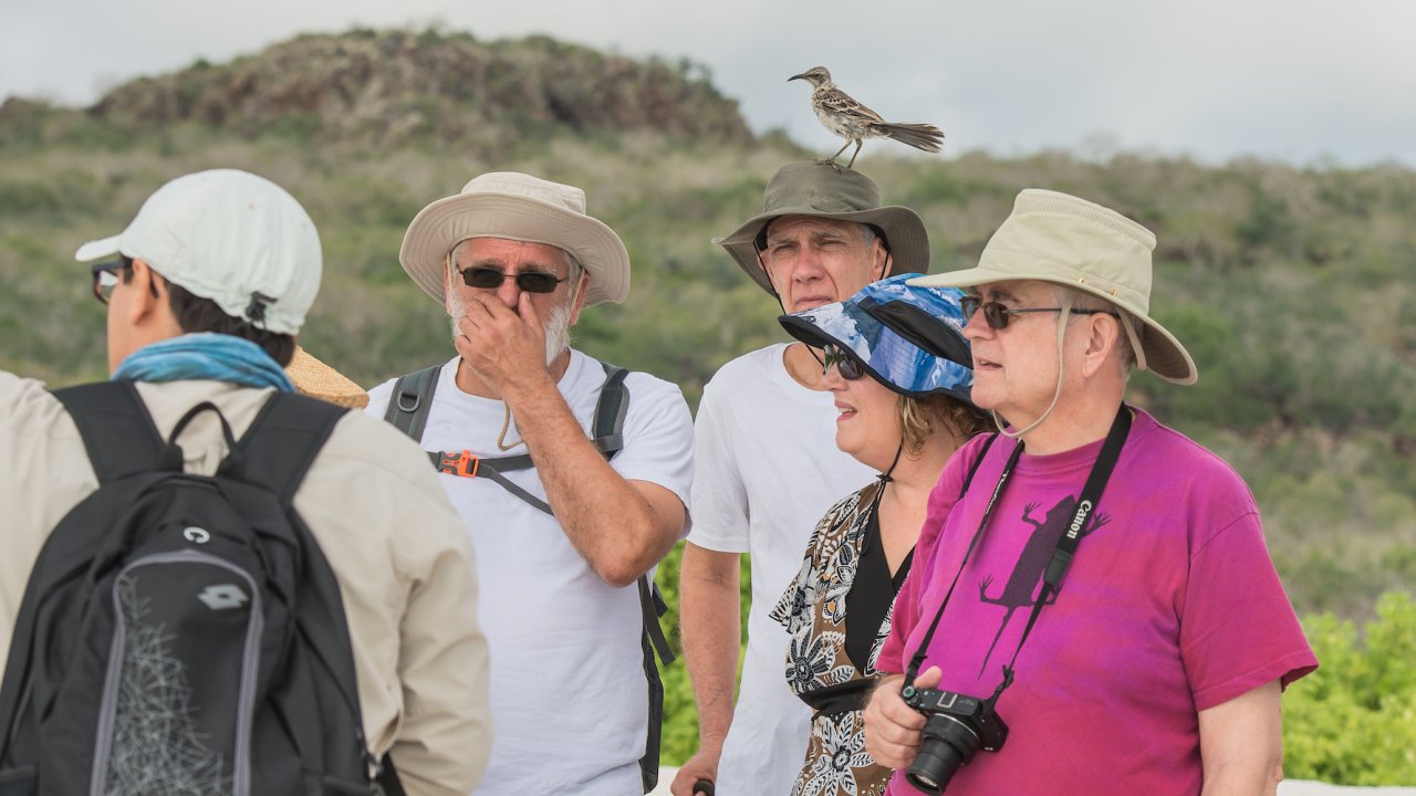 A group of people gathered together listening to their guide on a hike in the Galapagos
