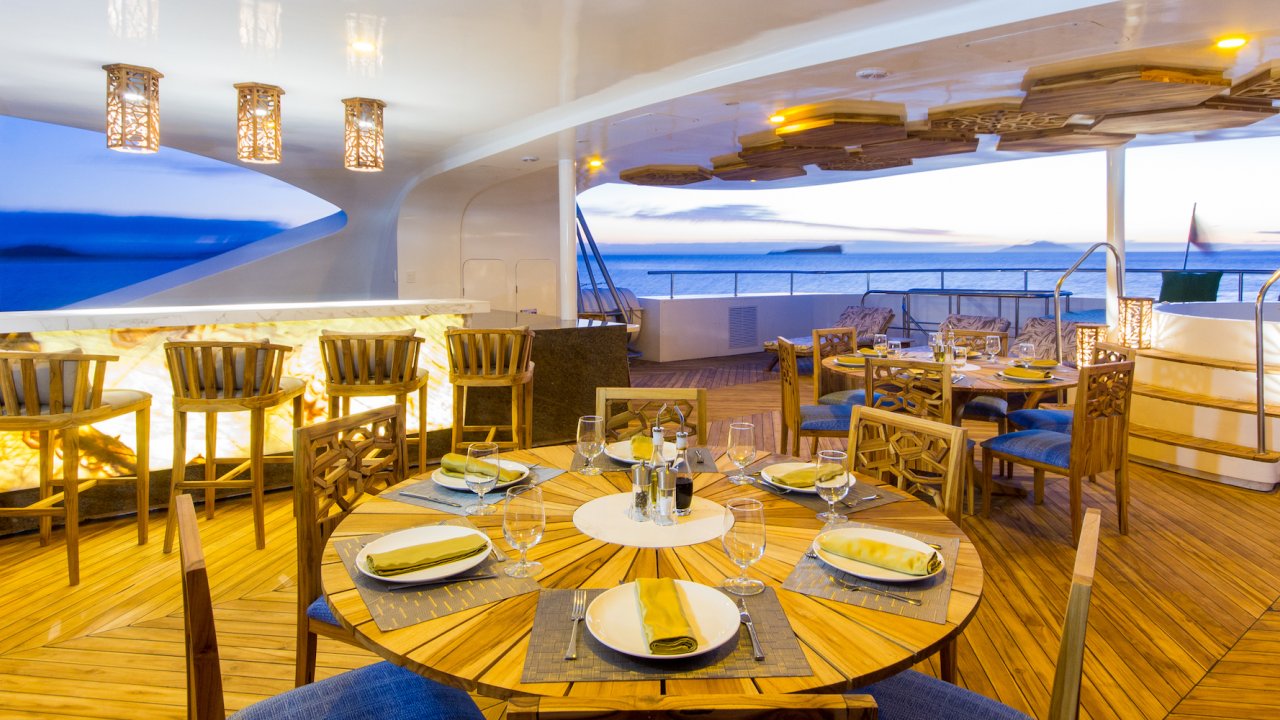 Sky deck on a catamaran cruise ship with tables set up for dining outside