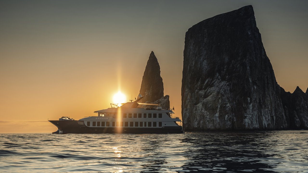 Small yacht cruising past Kicker Rock in the Galapagos Islands