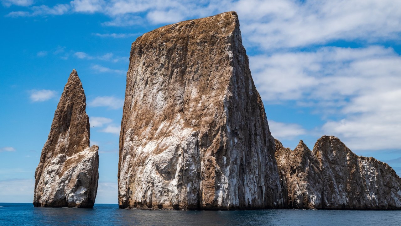 Dramatic cliffs of Kicker Rock rising from the ocean under blue skies, a highlight stop on many Galapagos family vacations.