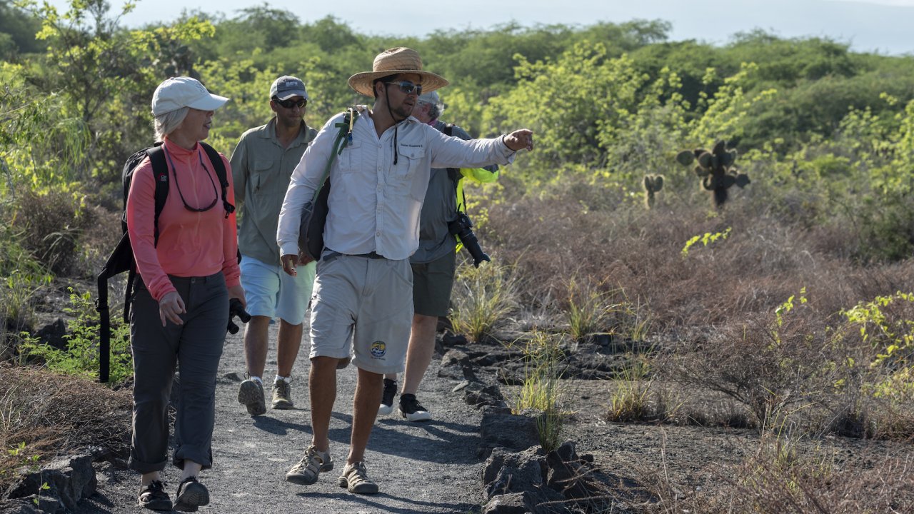 A group of people with a guide hiking through cacti in the Galapagos Islands