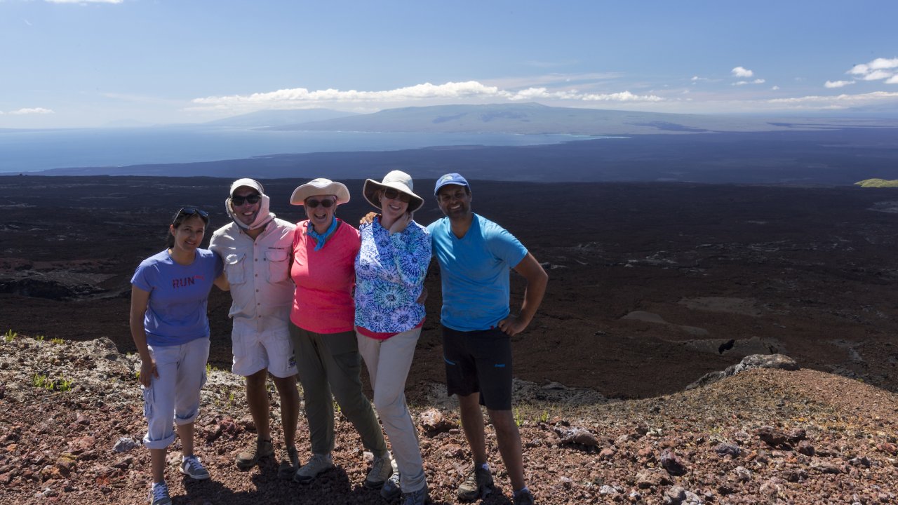 A group of tourist pose for a photo at the top of a volcano hike in the Galapagos 