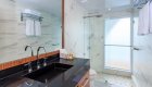 Modern bathroom with granite vanity and sink and tiled glass walk-in shower on a luxury yacht