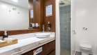 Bathroom sink and vanity with toilet and tiled shower in the background aboard a small luxury yacht