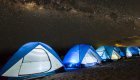 A group of tents lit up at night underneath the milky wear and starry night sky on an exclusive beach in the Galápagos Islands
