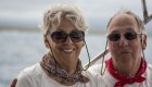 A man and woman couple with bandanas around their neck and sunglasses on smiling on a boat