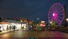 Families exploring a lively waterfront market at night with a glowing Ferris wheel during a Galapagos trip.