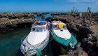 Two boats right next to each other in a rocky cove with cacti somewhere in the Galapagos Islands