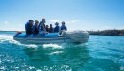 A group of people on a small raft wearing matching life jackets getting shuttled from their cruise ship in the Galapagos