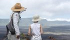 A guide and child in sun hats overlooking a volcanic landscape during a scenic hike on a Galapagos family vacation.