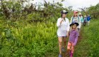 Mom and daughter in front of other tourists on a trail through lush green forests in one of the Galapagos National Parks